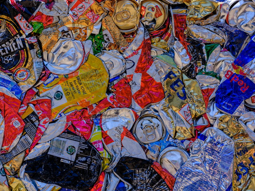 A large collection of discarded household items and waste materials arranged outdoors on a paved surface. Visible objects include several cardboard boxes, some flattened and others upright, along with